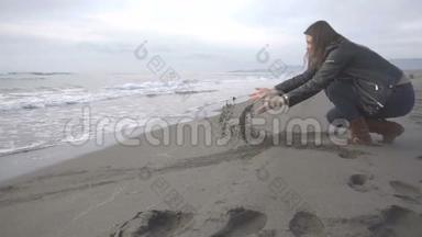 一个女孩在沙滩上捡沙子并让沙子掉下来的慢镜头